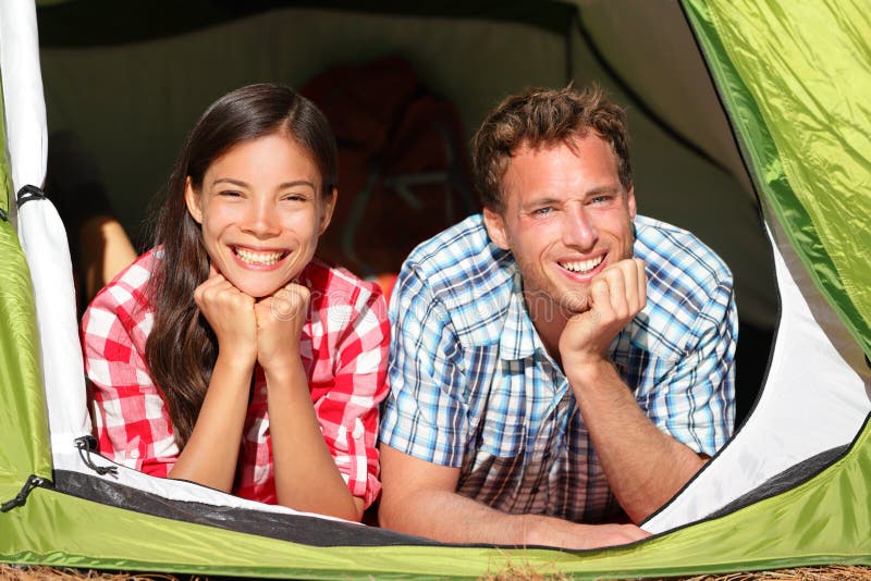 Gelukkig romantisch paar die in tent het kijken kamperen stock foto Gelukkig romantisch paar die in tent het kijken kamperen stock foto