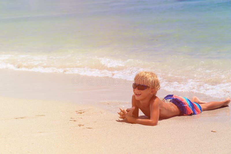 Gelukkig weinig die jongen op strand wordt ontspannen stock foto Gelukkig weinig die jongen op strand wordt ontspannen stock foto