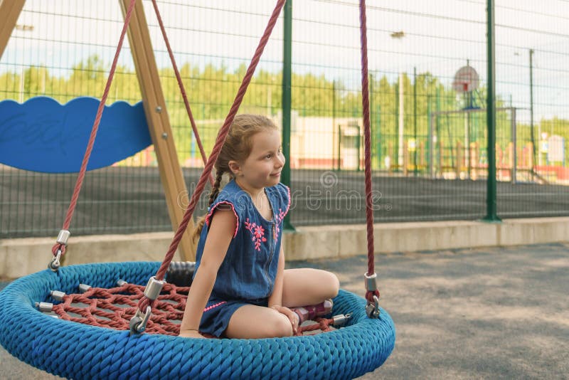 Gelukkig weinig kindmeisje die en op een schommeling in het stadspark lachen slingeren in de zomer royalty-vrije stock afbeelding Gelukkig weinig kindmeisje die en op een schommeling in het stadspark lachen slingeren in de zomer royalty-vrije stock afbeelding