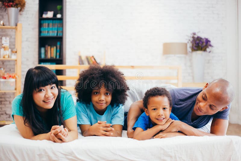 Gelukkige Afrikaanse Amerikaanse familie die thuis op bed leggen die, gelukkig aan elkaar spreken Ouderschap en familieconcept royalty-vrije stock foto's Gelukkige Afrikaanse Amerikaanse familie die thuis op bed leggen die, gelukkig aan elkaar spreken Ouderschap en familieconcept royalty-vrije stock foto's