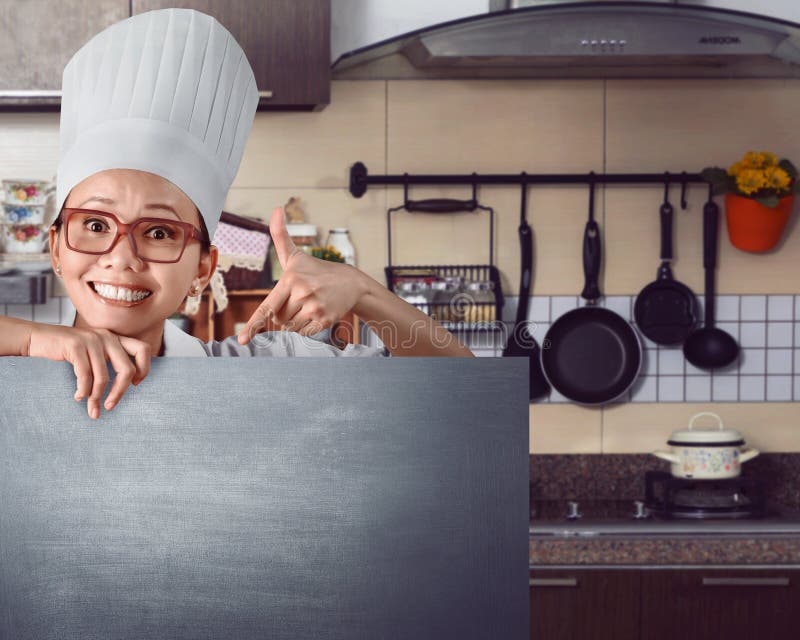 Gelukkige Aziatische chef-kok die menuteken op bord tonen stock afbeeldingen Gelukkige Aziatische chef-kok die menuteken op bord tonen stock afbeeldingen