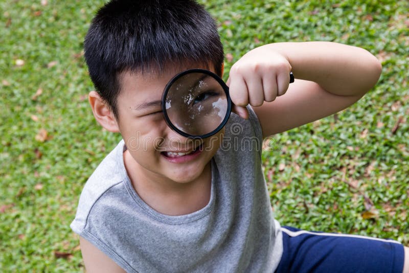 Gelukkige Aziatische Chinees weinig jongen die door vergrootglas kijken royalty-vrije stock foto's Gelukkige Aziatische Chinees weinig jongen die door vergrootglas kijken royalty-vrije stock foto's