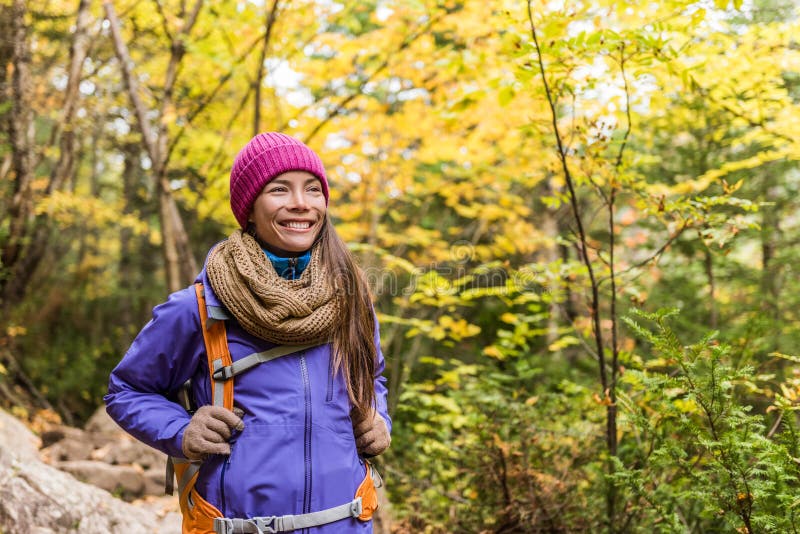 Gelukkige Aziatische vrouw die in de herfst bosaard wandelen die op sleepweg lopen Wandelaarmeisje met rugzak, hoed, sjaal en jas stock afbeelding Gelukkige Aziatische vrouw die in de herfst bosaard wandelen die op sleepweg lopen Wandelaarmeisje met rugzak, hoed, sjaal en jas stock afbeelding