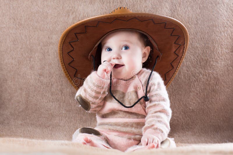 Gelukkige baby die de uitrusting van het koemeisje met grote hoed dragen