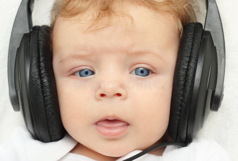 Gelukkige babyjongen in oortelefoons stock fotografie Gelukkige babyjongen in oortelefoons stock fotografie