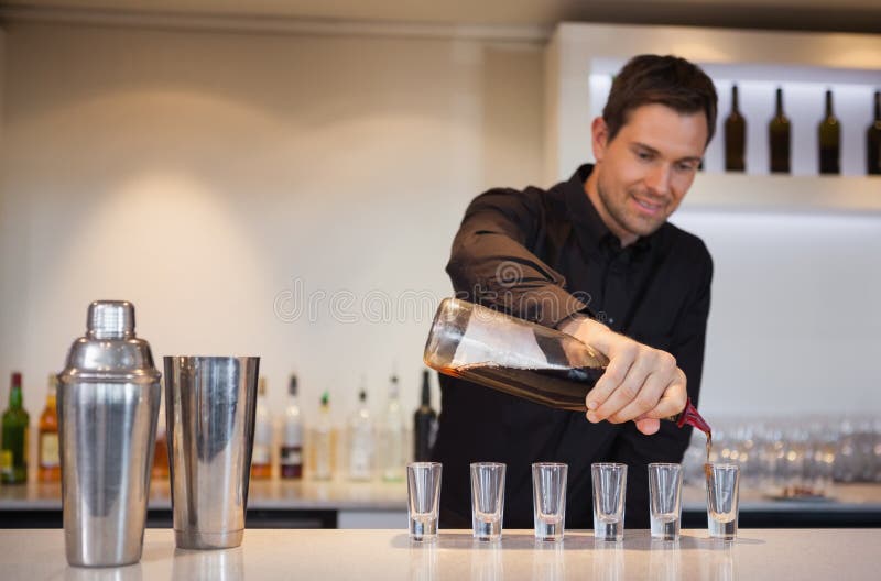 Gelukkige barman gietende cocktail in geschotene glazen royalty-vrije stock fotografie Gelukkige barman gietende cocktail in geschotene glazen royalty-vrije stock fotografie