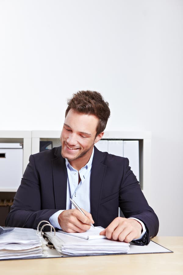 Happy business man taking notes in files in office. Happy business man taking notes in files in office