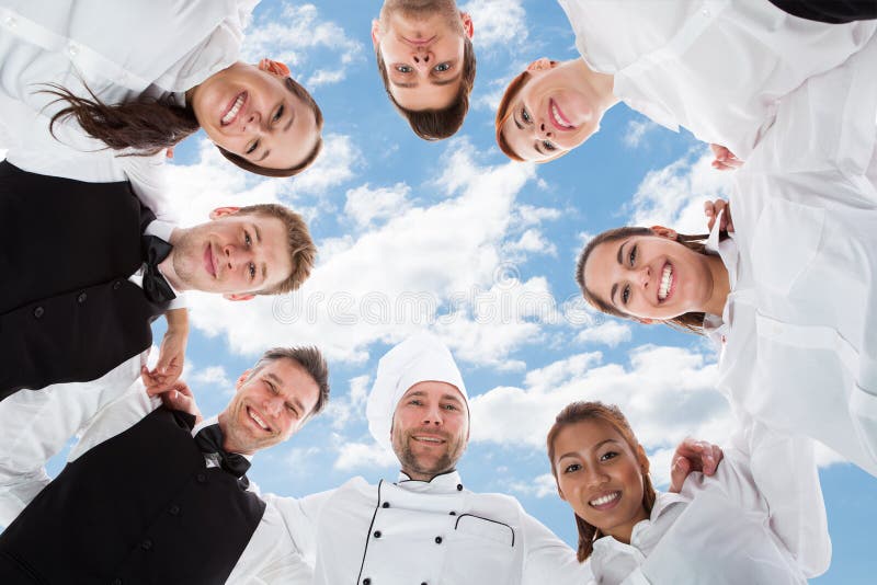 Gelukkige chef-kok en kelners die zich in wirwar tegen hemel bevinden stock foto's Gelukkige chef-kok en kelners die zich in wirwar tegen hemel bevinden stock foto's