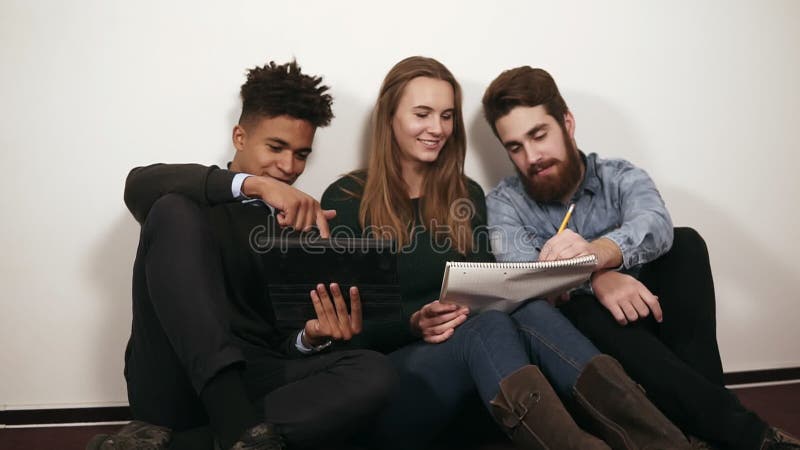 Gelukkige diverse groep studenten of jong commercieel team die aan een project werken Zij zitten op de vloer en het werken