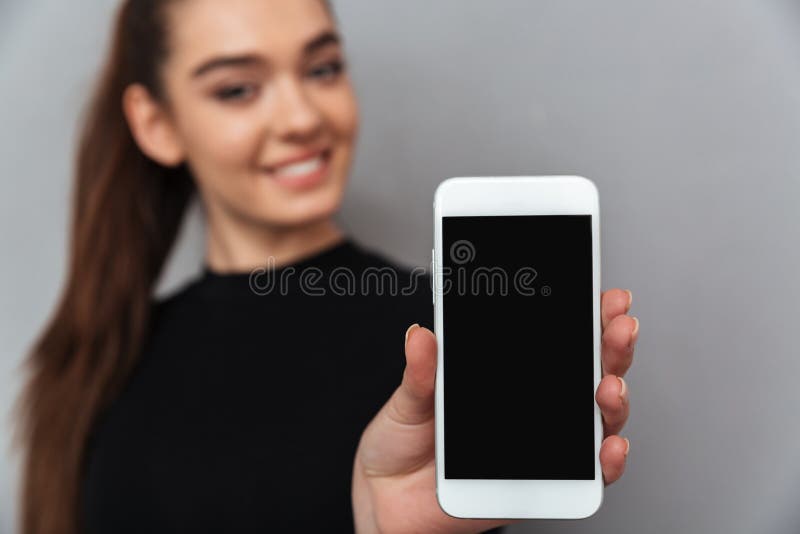 Gelukkige donkerbruine vrouw in zwarte kleren die lege smartphone s tonen royalty-vrije stock afbeelding Gelukkige donkerbruine vrouw in zwarte kleren die lege smartphone s tonen royalty-vrije stock afbeelding