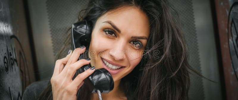 Gelukkige en glimlachende vrouw die in de retro telefooncel spreken royalty-vrije stock afbeeldingen Gelukkige en glimlachende vrouw die in de retro telefooncel spreken royalty-vrije stock afbeeldingen