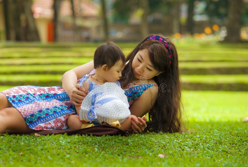 Gelukkige en speelse Aziatische Chinese vrouw als het houden van van moeder die van met zoete en mooie het meisjeszitting van de stock fotografie Gelukkige en speelse Aziatische Chinese vrouw als het houden van van moeder die van met zoete en mooie het meisjeszitting van de stock fotografie