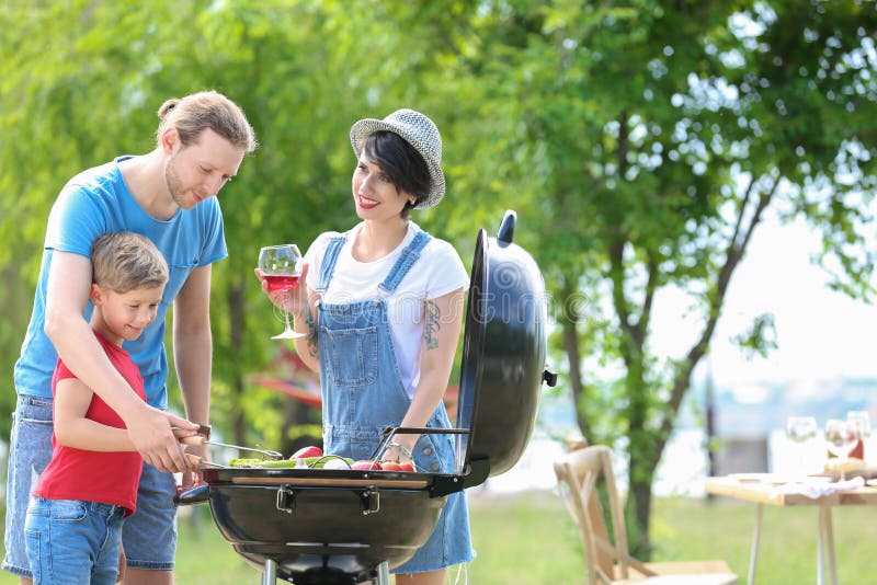 Gelukkige familie die barbecue met moderne grill hebben royalty-vrije stock afbeelding Gelukkige familie die barbecue met moderne grill hebben royalty-vrije stock afbeelding