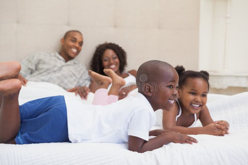 Gelukkige familie die bij bed het glimlachen liggen royalty-vrije stock foto's Gelukkige familie die bij bed het glimlachen liggen royalty-vrije stock foto's