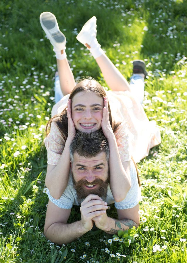 Gelukkige familie die op bloemrijke weide liggen Gebaarde mens en zijn vrij donkerbruine dochter op picknick in platteland mooi stock fotografie Gelukkige familie die op bloemrijke weide liggen Gebaarde mens en zijn vrij donkerbruine dochter op picknick in platteland mooi stock fotografie