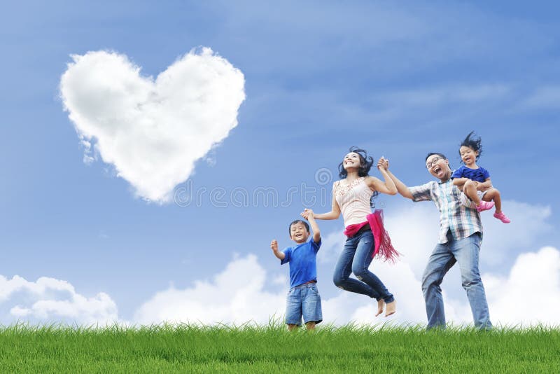 Happy family is having fun under love shape clouds in the park. Happy family is having fun under love shape clouds in the park