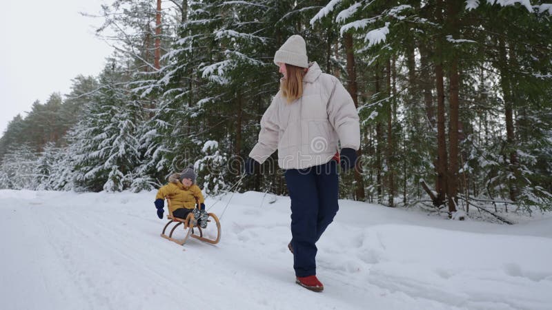 Gelukkige familie in het sneeuwwoud in het weekend trekt moeder zich in de mouwen met kleine kindvrouw en kind