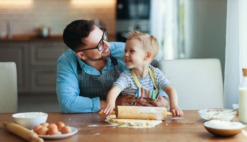 Happy family in kitchen. Father and child son baking cookies together. Happy family in kitchen. Father and child son baking cookies together