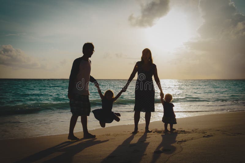 Gelukkige familie met jonge geitjes op spel op zonsondergangstrand royalty-vrije stock afbeeldingen Gelukkige familie met jonge geitjes op spel op zonsondergangstrand royalty-vrije stock afbeeldingen