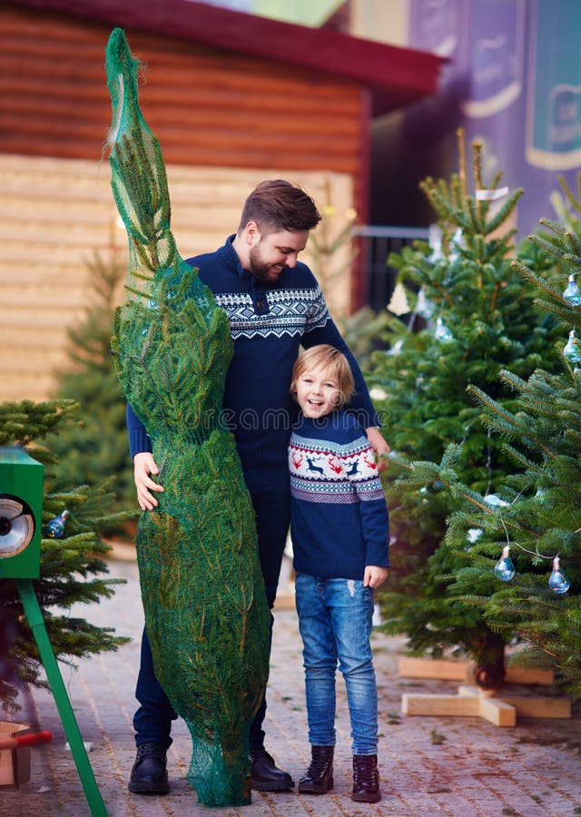 Gelukkige familie, vader en zoon die een Kerstmisboom kopen voor de wintervakantie bij seizoengebonden markt stock foto Gelukkige familie, vader en zoon die een Kerstmisboom kopen voor de wintervakantie bij seizoengebonden markt stock foto