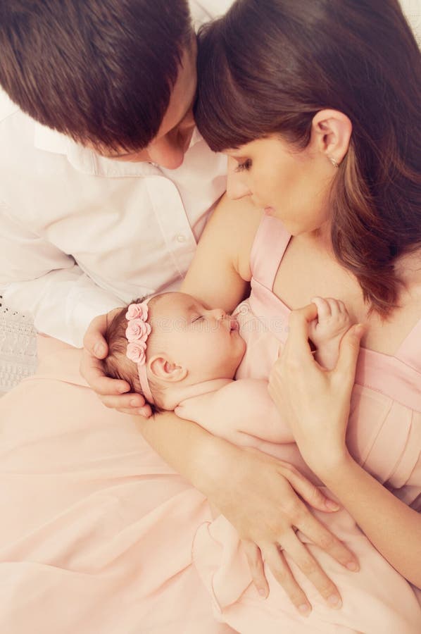 Gelukkige familie van twee die het leuke meisje van de slaap pasgeboren baby houden stock afbeelding Gelukkige familie van twee die het leuke meisje van de slaap pasgeboren baby houden stock afbeelding