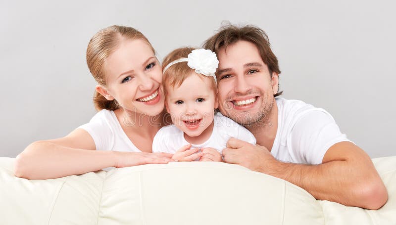 Happy family mother, father, child baby daughter at home on the sofa playing and laughing. Happy family mother, father, child baby daughter at home on the sofa playing and laughing