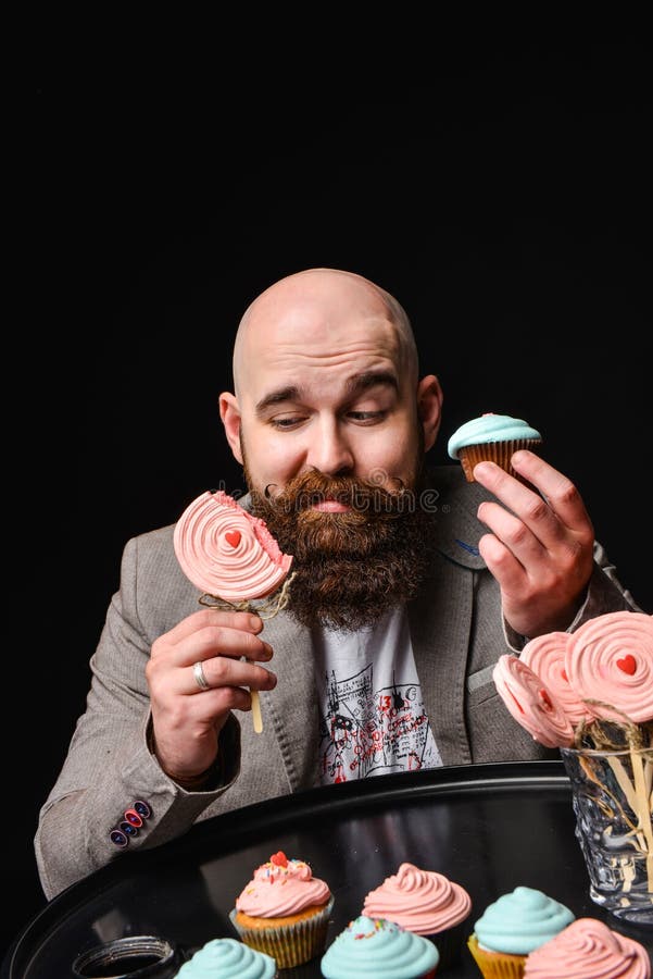 Gelukkige gebaarde kale mens die twee roomcakes op zwarte achtergrond houden royalty-vrije stock afbeeldingen Gelukkige gebaarde kale mens die twee roomcakes op zwarte achtergrond houden royalty-vrije stock afbeeldingen