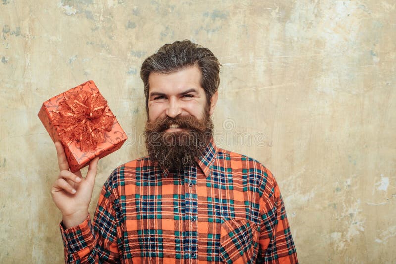 Gelukkige gebaarde mens die met rode giftdoos glimlachen met boog stock afbeeldingen Gelukkige gebaarde mens die met rode giftdoos glimlachen met boog stock afbeeldingen