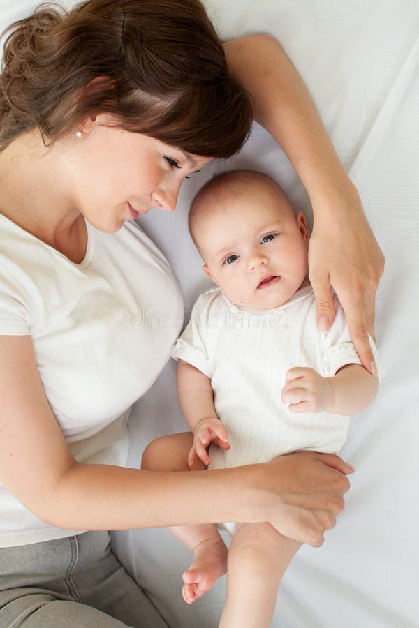 Gelukkige glimlachende moeder en haar baby die op bed thuis liggen, hoogste mening royalty-vrije stock foto's Gelukkige glimlachende moeder en haar baby die op bed thuis liggen, hoogste mening royalty-vrije stock foto's