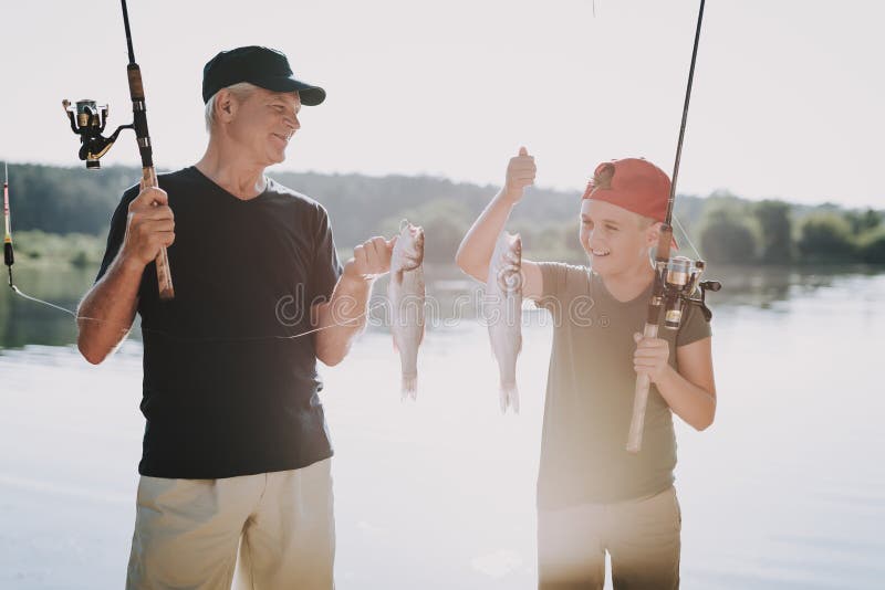 Gelukkige Grootvader en Kleinzoon die op Rivier vissen royalty-vrije stock fotografie Gelukkige Grootvader en Kleinzoon die op Rivier vissen royalty-vrije stock fotografie