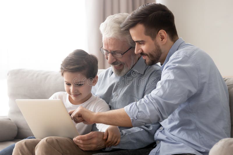 Gelukkige grootvader en vader leren kleine jongen om laptop te gebruiken
