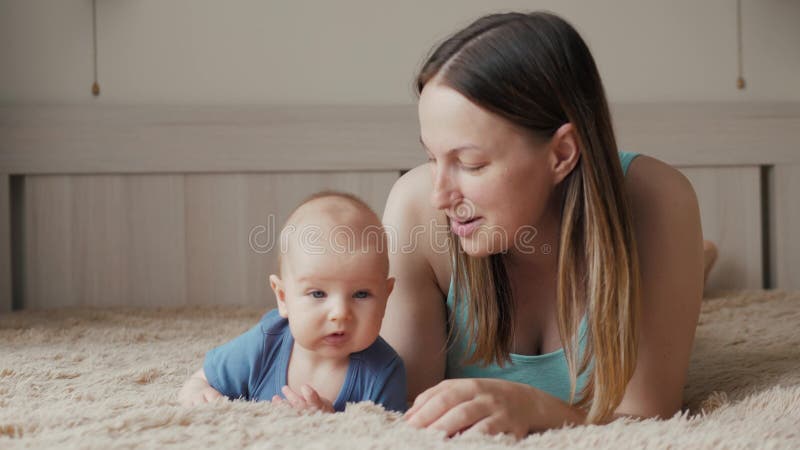 Gelukkige houdende van familie De jonge moeder speelt met haar babymeisje in de slaapkamer Het mamma en het kind hebben pret op h