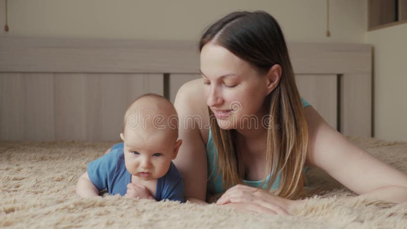 Gelukkige houdende van familie De jonge moeder speelt met haar babymeisje in de slaapkamer Het mamma en het kind hebben pret op h