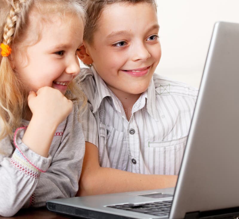 Gelukkige jonge geitjes die laptop thuis spelen royalty-vrije stock fotografie Gelukkige jonge geitjes die laptop thuis spelen royalty-vrije stock fotografie