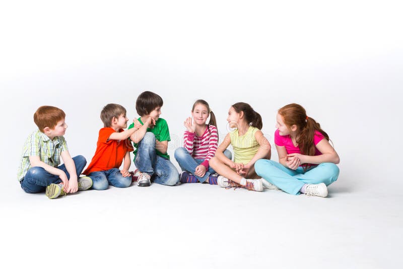 Gelukkige jonge geitjes die op vloer bij studio, exemplaarruimte zitten stock fotografie Gelukkige jonge geitjes die op vloer bij studio, exemplaarruimte zitten stock fotografie