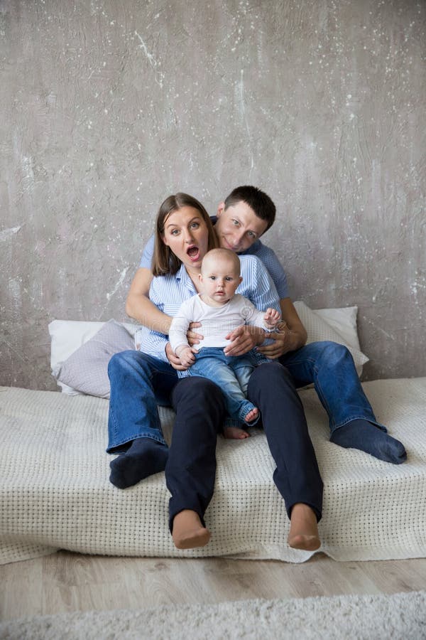 Gelukkige Jonge Kaukasische Familiezitting op Bed stock foto Gelukkige Jonge Kaukasische Familiezitting op Bed stock foto