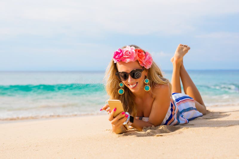 Gelukkige jonge vrouw die op het strand in zand liggen en mobiele telefoon met behulp van stock afbeeldingen Gelukkige jonge vrouw die op het strand in zand liggen en mobiele telefoon met behulp van stock afbeeldingen