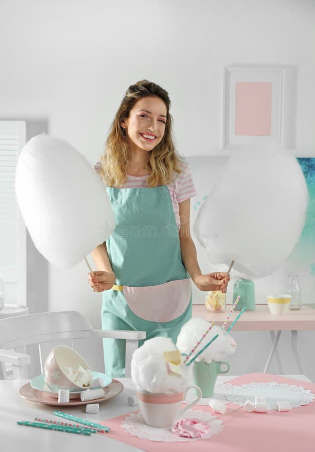 Gelukkige jonge vrouw met gesponnen suiker en snoepjes op lijst stock foto Gelukkige jonge vrouw met gesponnen suiker en snoepjes op lijst stock foto