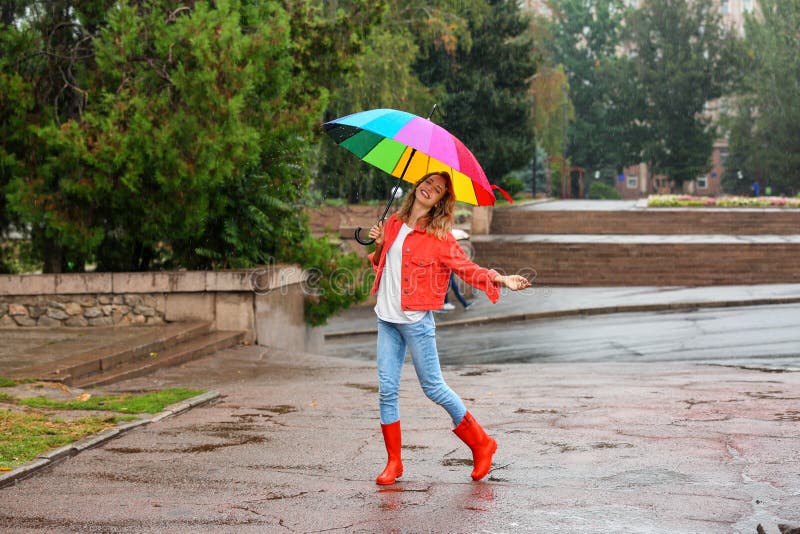 Happy young woman with bright umbrella under rain outdoors. Happy young woman with bright umbrella under rain outdoors