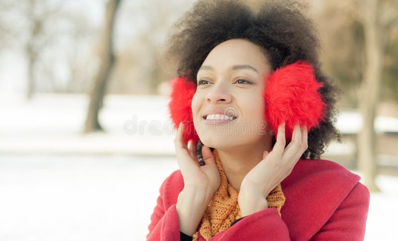 Gelukkige jonge vrouw met warm op oren die de winter van zonneschijn genieten stock foto Gelukkige jonge vrouw met warm op oren die de winter van zonneschijn genieten stock foto