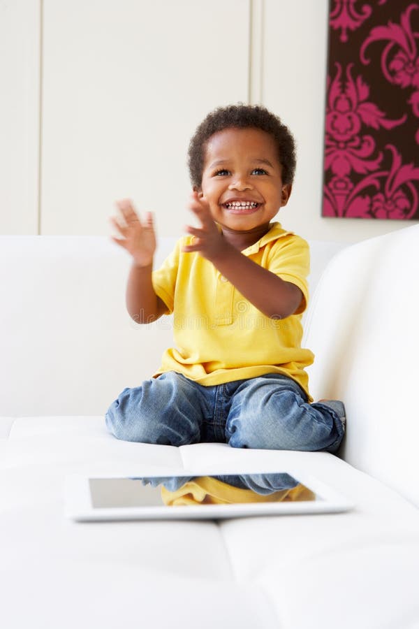 Gelukkige Jongen op Sofa Playing With Digital Tablet royalty-vrije stock afbeelding Gelukkige Jongen op Sofa Playing With Digital Tablet royalty-vrije stock afbeelding