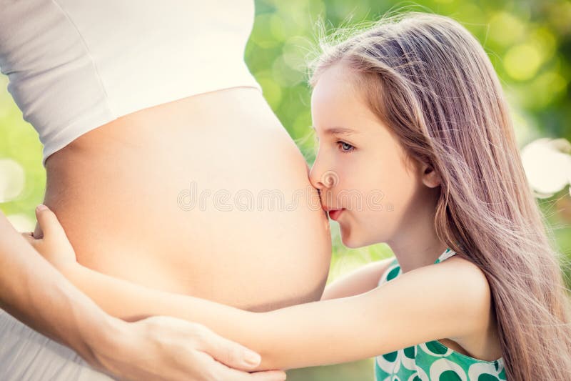 Gelukkige kind het kussen buik van zwangere vrouw stock fotografie Gelukkige kind het kussen buik van zwangere vrouw stock fotografie