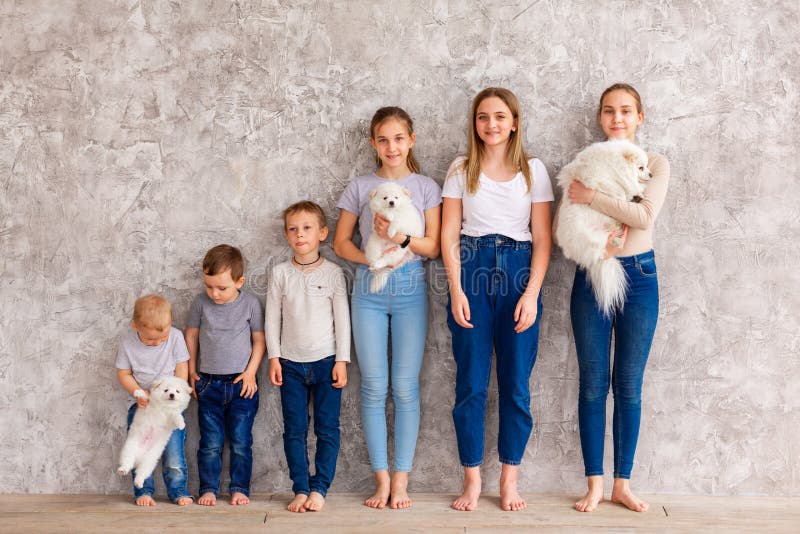 Gelukkige kinderen van verschillende leeftijd met puppies in lijn