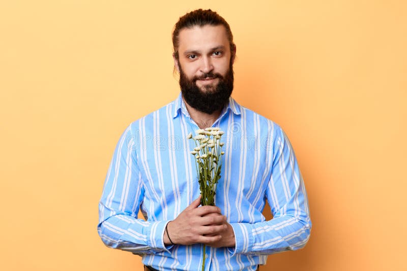 Gelukkige knappe vrolijke positieve jonge mens die een bos van bloemen houden royalty-vrije stock afbeelding Gelukkige knappe vrolijke positieve jonge mens die een bos van bloemen houden royalty-vrije stock afbeelding