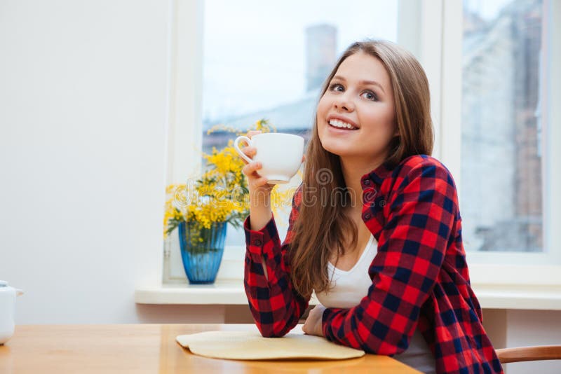 Gelukkige leuke jonge vrouw die coffe op keuken thuis drinken royalty-vrije stock foto Gelukkige leuke jonge vrouw die coffe op keuken thuis drinken royalty-vrije stock foto