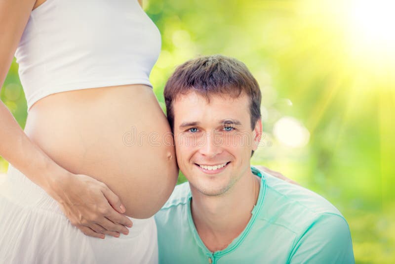Gelukkige man holdingsbuik van zwangere vrouw stock fotografie Gelukkige man holdingsbuik van zwangere vrouw stock fotografie