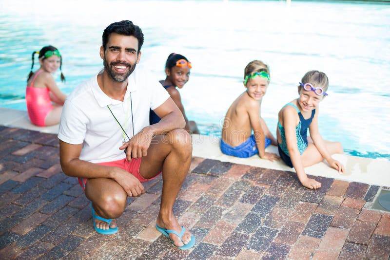 Gelukkige mannelijke instructeur en studenten bij poolside stock afbeelding Gelukkige mannelijke instructeur en studenten bij poolside stock afbeelding