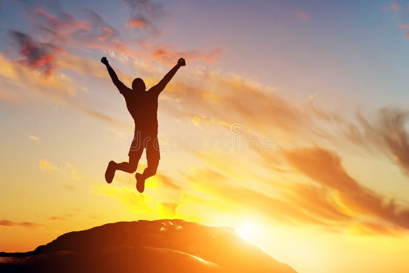 Gelukkige mens die voor vreugde op de piek van de berg bij zonsondergang springen Succes
