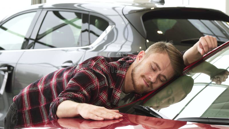 Gelukkige mens die zijn nieuwe auto strijken die zacht tonend duimen bij het handel drijven glimlachen