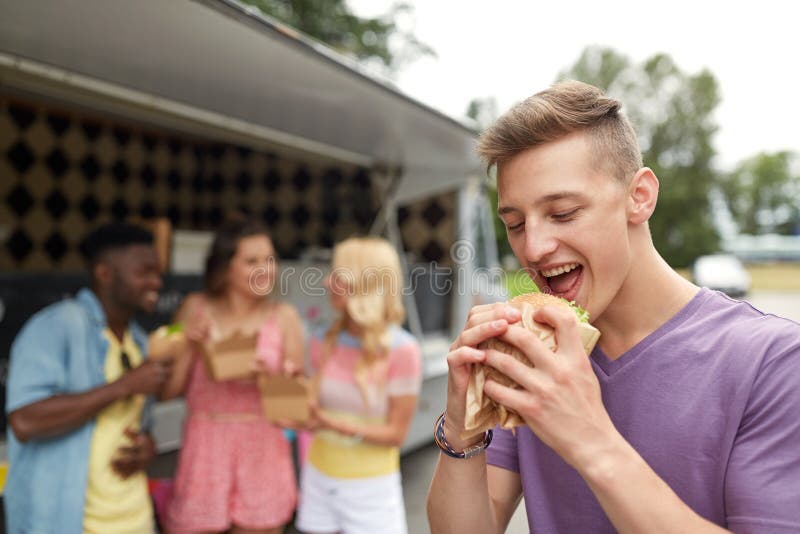 Gelukkige mens met hamburger en vrienden bij voedselvrachtwagen royalty-vrije stock foto's Gelukkige mens met hamburger en vrienden bij voedselvrachtwagen royalty-vrije stock foto's